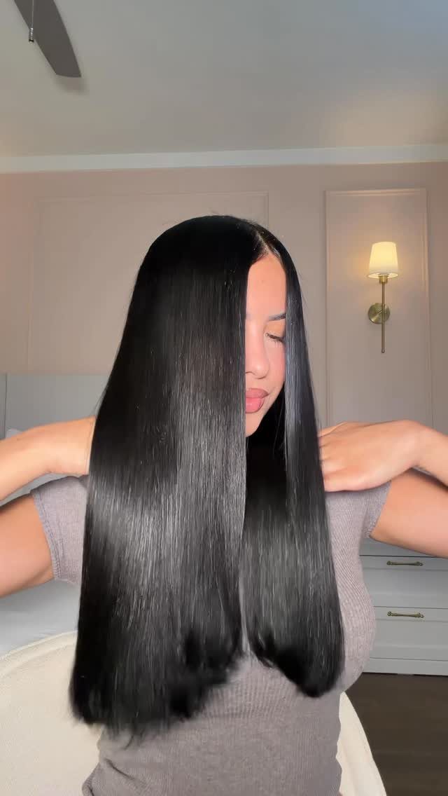 Korean Glass Hair: 6 Sleek and Shiny Styles to Try 2 Woman with long, straight, glossy black hair reflecting light in a bright room.