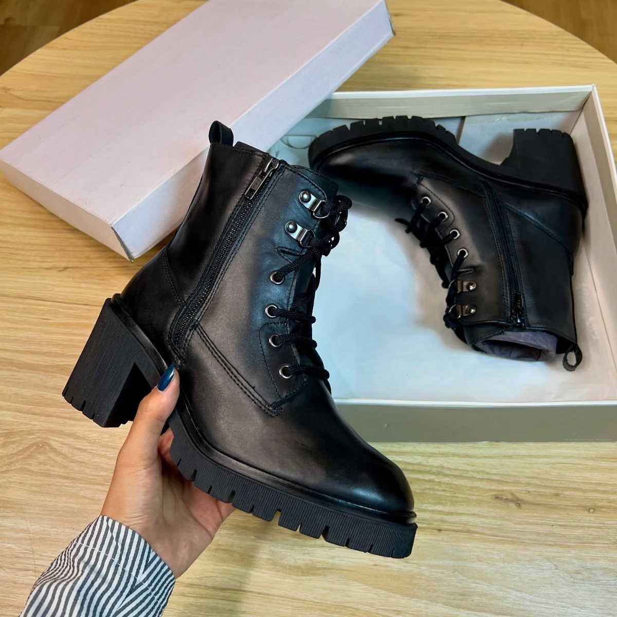 8 Leather High Heel Boots Ideas for Every Outfit 2 Black leather ankle boots with chunky block heels and laces on a wooden table