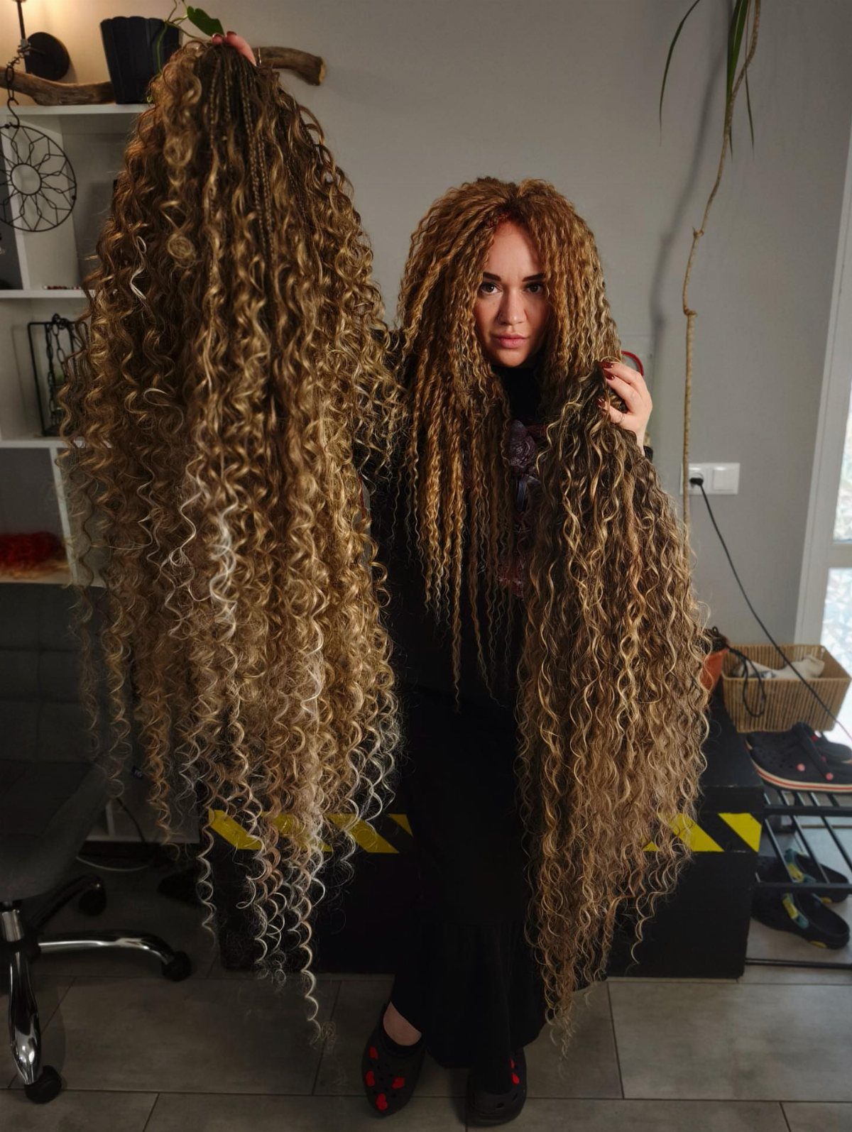 Long Russian Hair Ideas: 8 Looks, Colors and Textures 4 Woman with long curly blonde hair holding a large bundle of hair extensions.