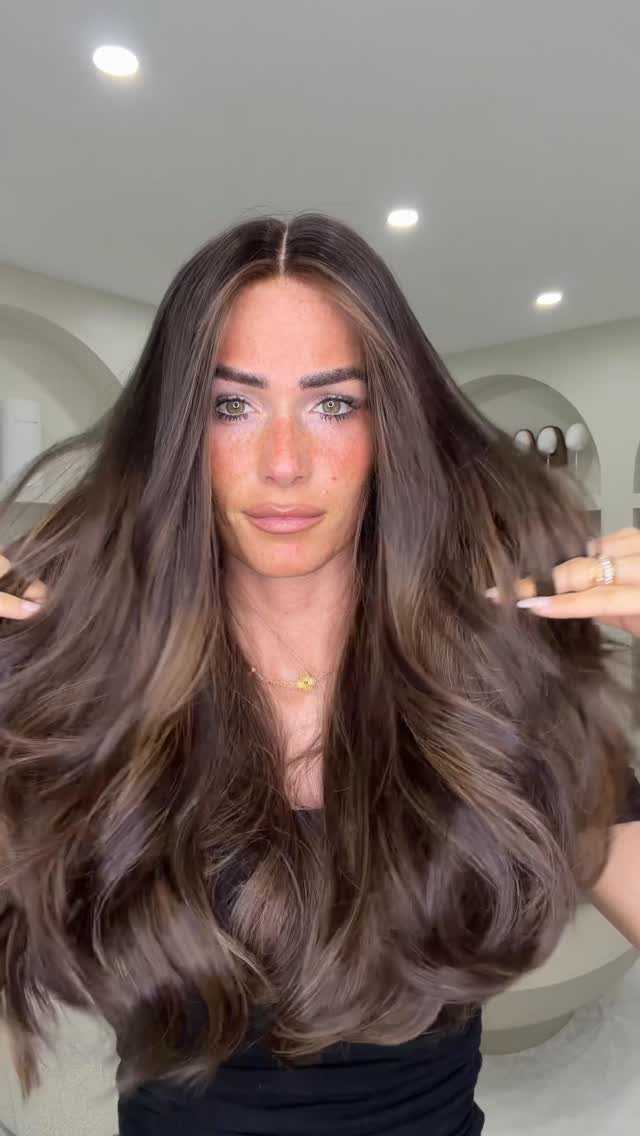 Long Russian Hair Ideas: 8 Looks, Colors and Textures 6 Woman with long, voluminous brown hair posing in a bright indoor room.