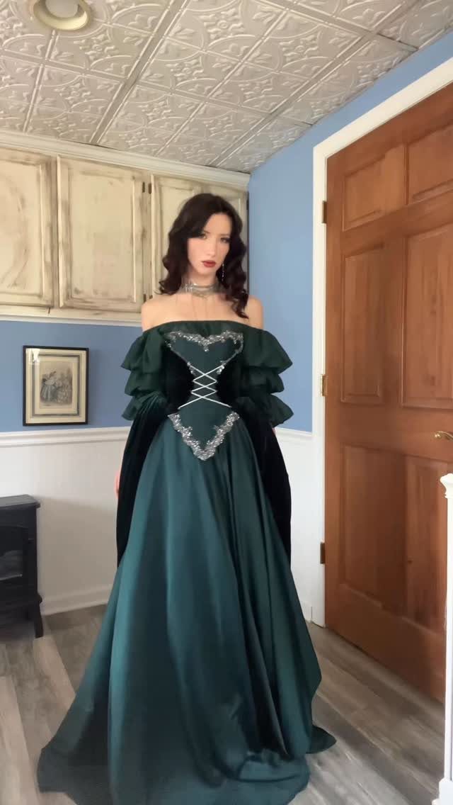Woman wearing a floor-length dark green satin gown with silver beaded embroidery.
