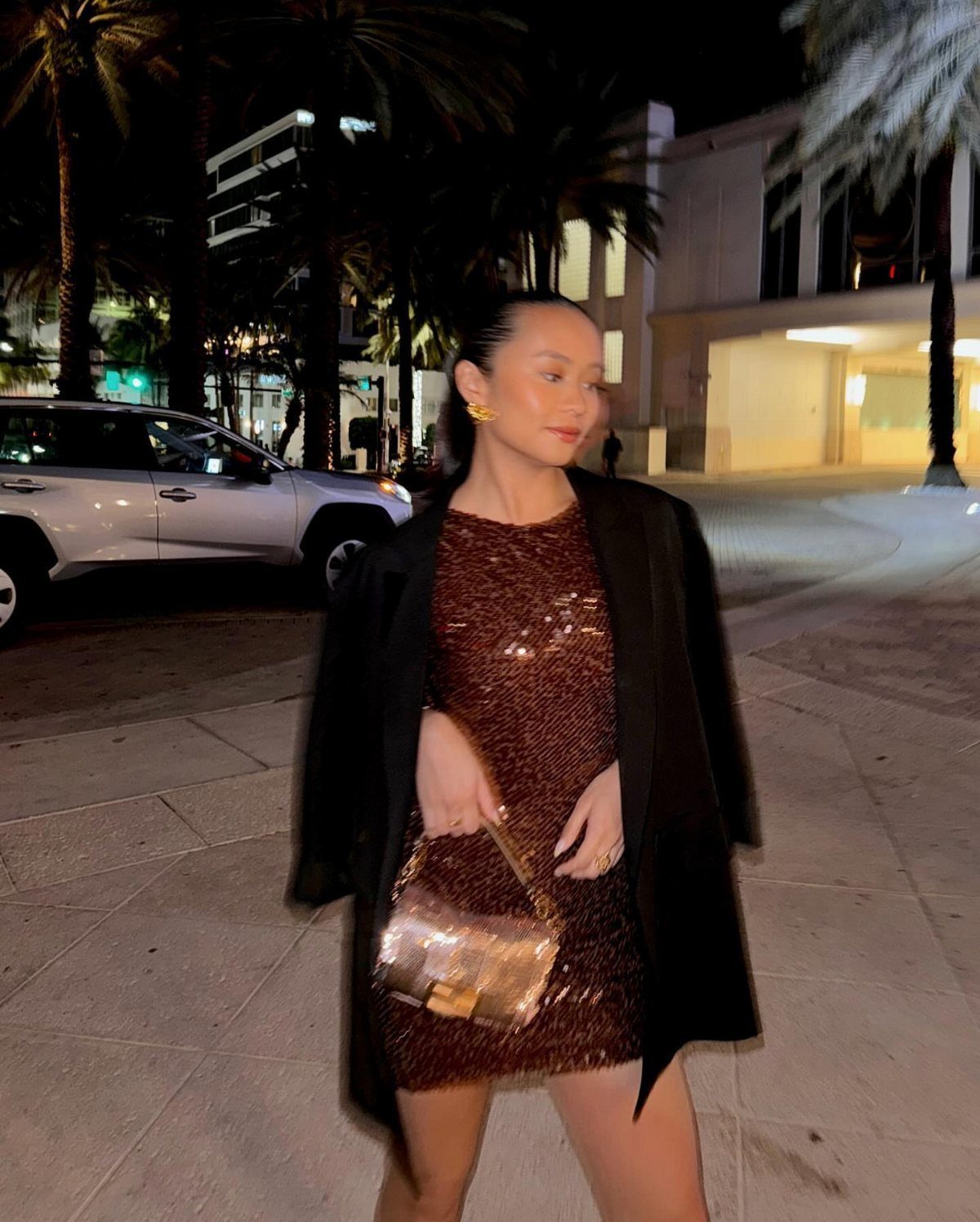 Miami Club Outfits: 8 Ideas for Day and Night 8 Woman in bronze sequin dress and black blazer posing at night in Miami.
