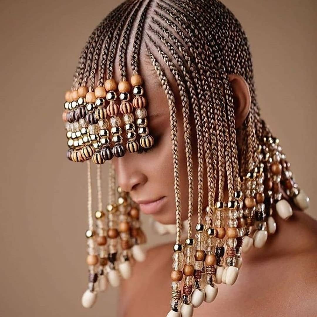 5 Middle Part Tribal Braids with Beads, Curls and More 1 Woman with middle part tribal braids decorated with gold and brown beads.