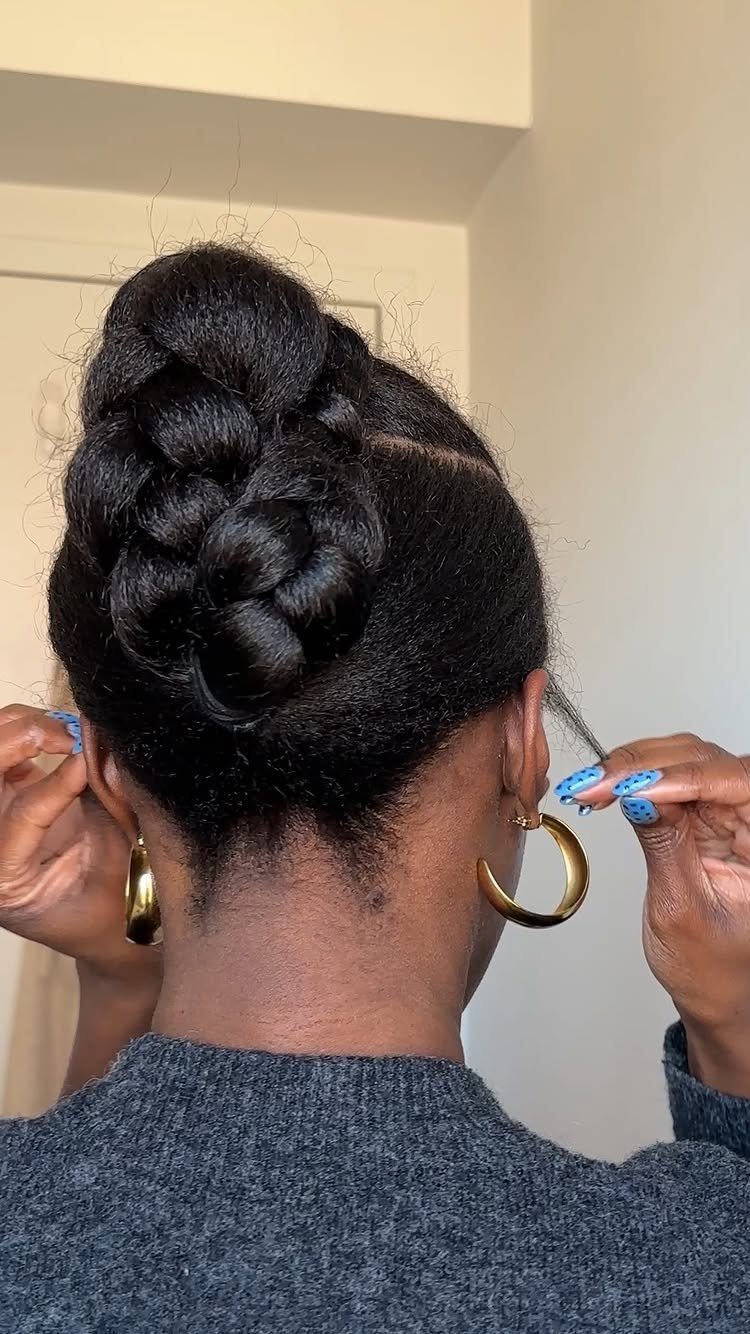 Braided updo bun on dark hair with gold hoop earrings and grey sweater.