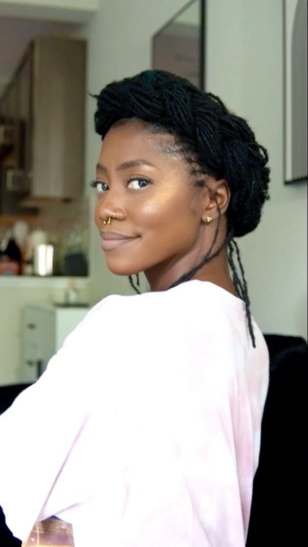 Woman with black braided hair styled in a halo braid updo wearing pink.