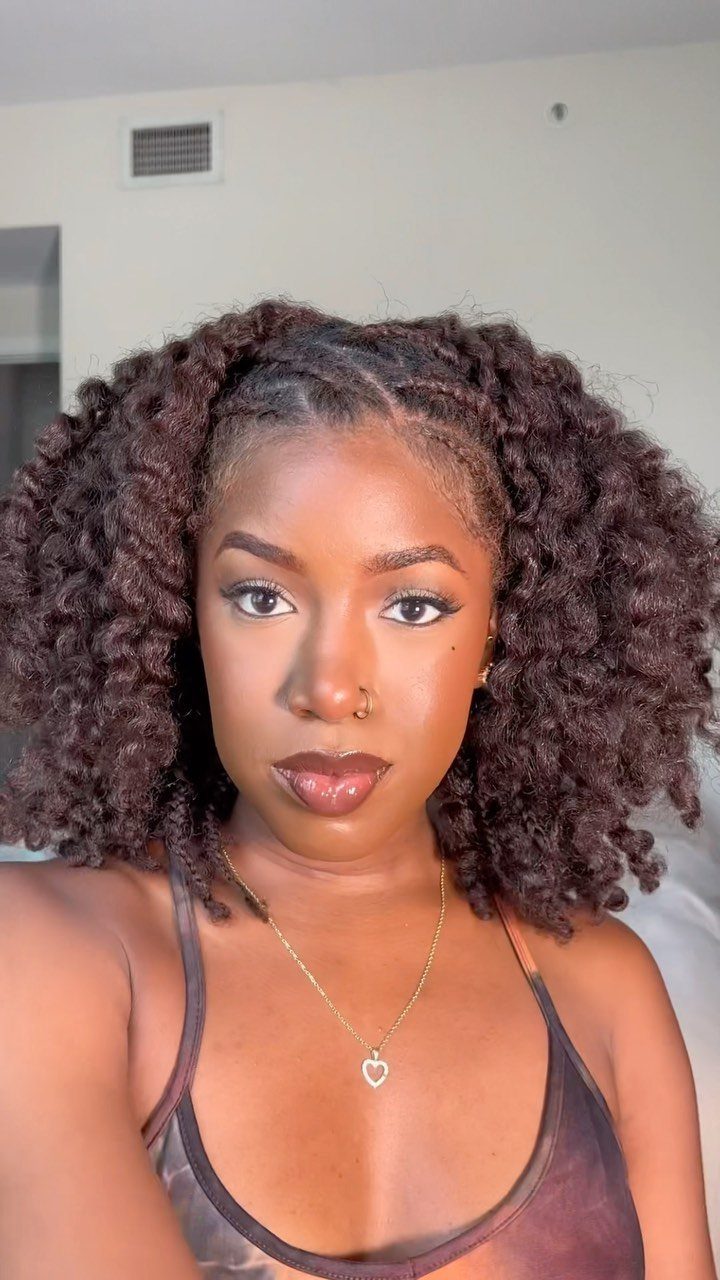 Woman with voluminous, defined curly natural hair and a gold heart necklace.