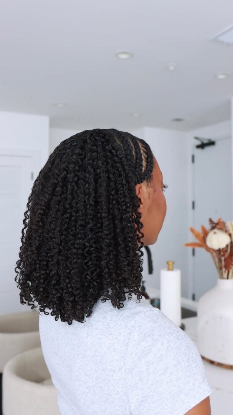Woman with shoulder-length tight black curls in a bright white room