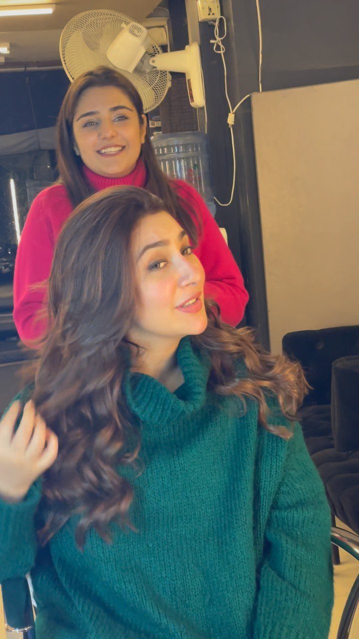 Natural Long Hairstyles: 10 Ideas, From Bantu Knots to Waves 4 Woman with long wavy brown hair wearing a green turtleneck sweater indoors.