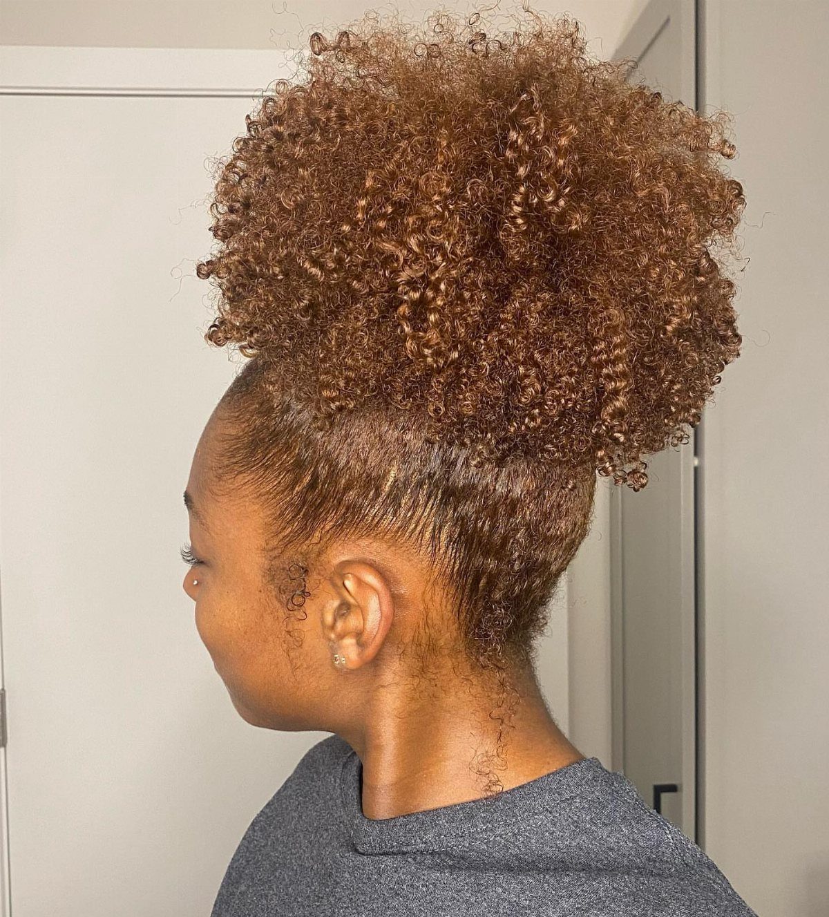 Natural Long Hairstyles: 10 Ideas, From Bantu Knots to Waves 2 Woman with brown curly hair styled in a voluminous high puff at the crown.