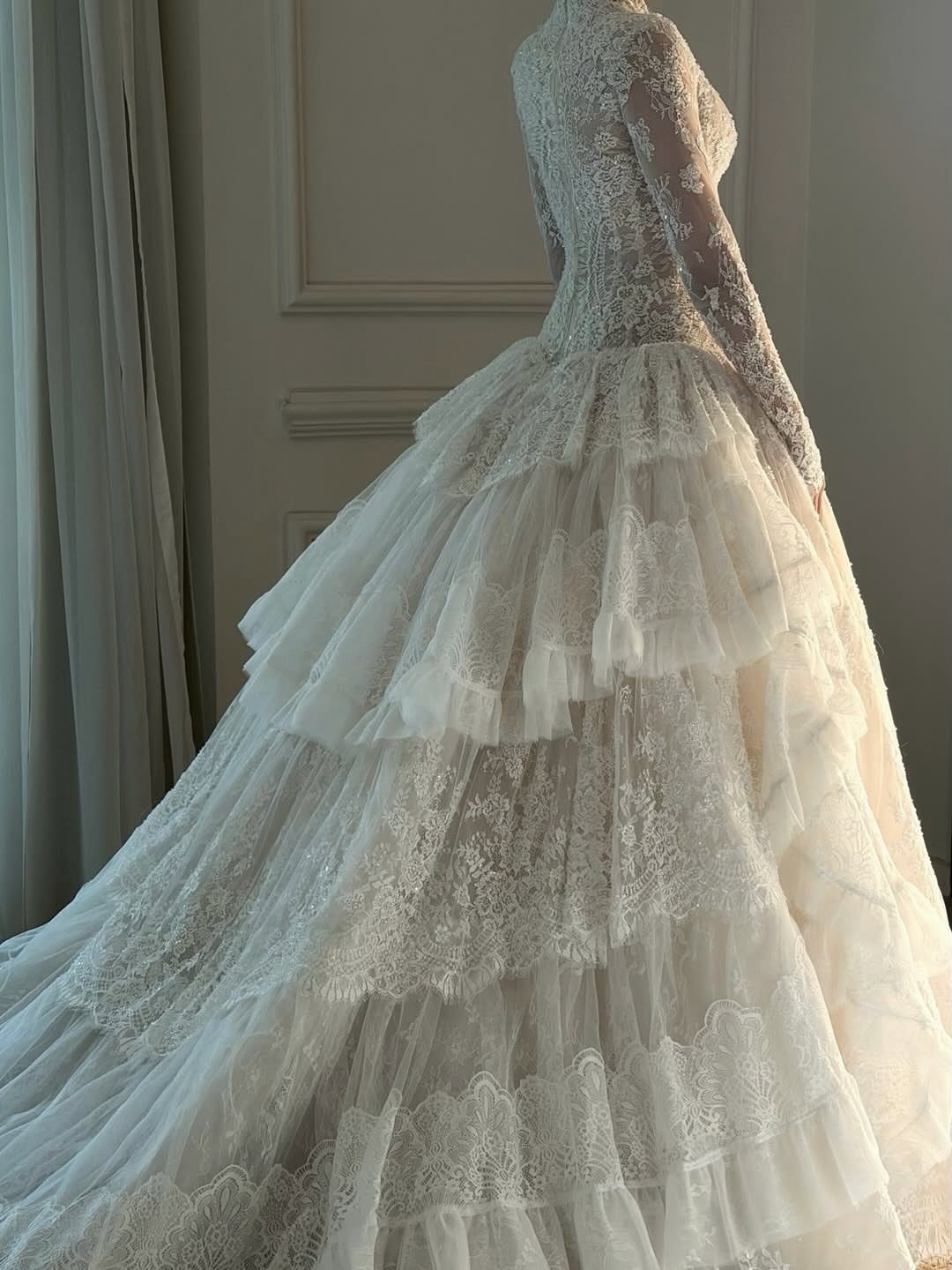 White lace wedding dress with long sleeves and a tiered tulle skirt.