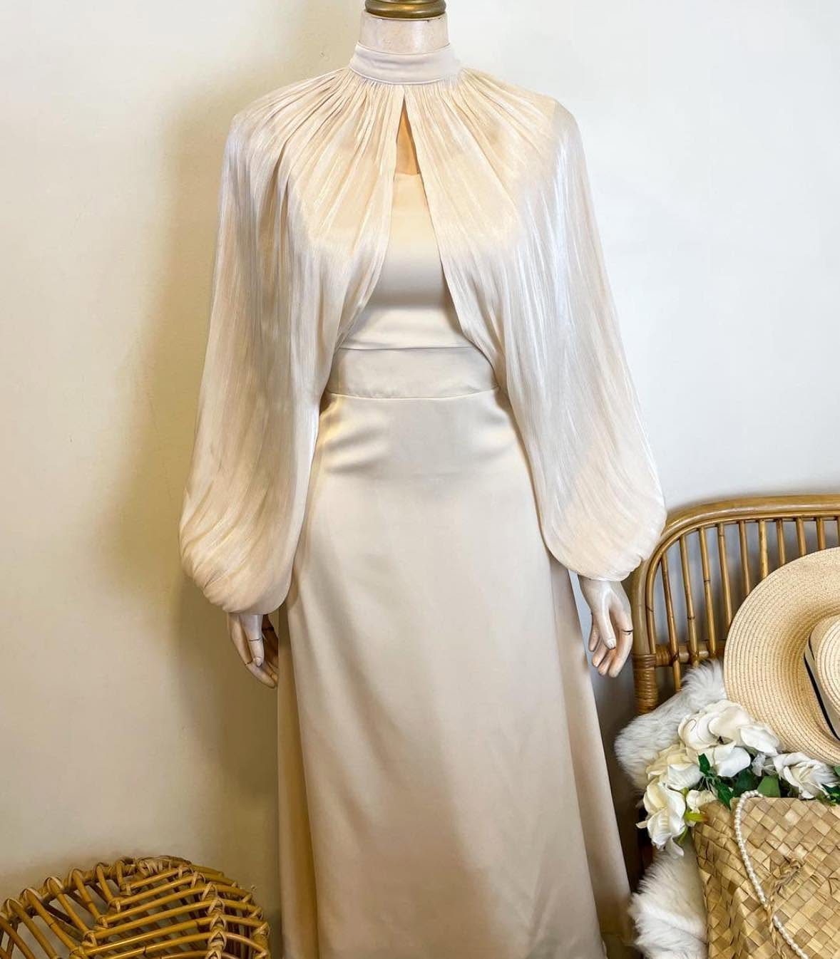 Champagne satin dress with a pleated capelet overlay displayed on a mannequin.