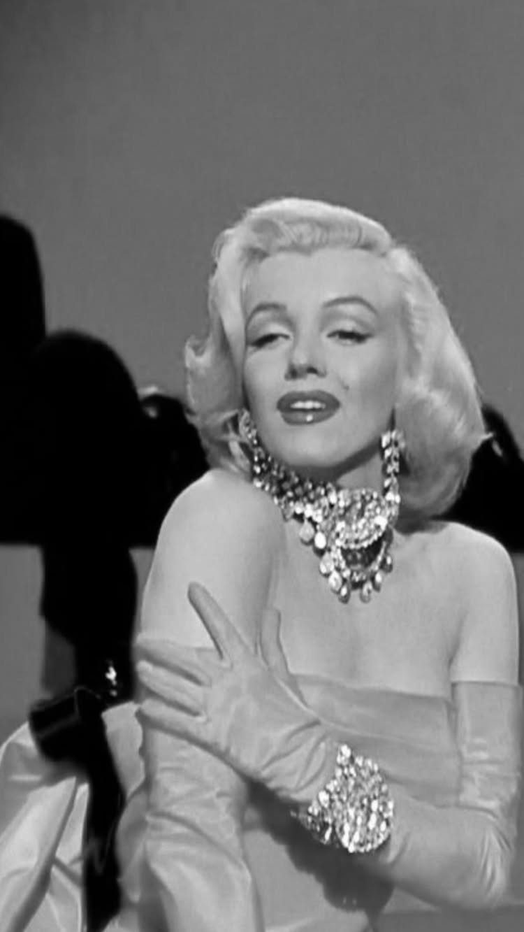 Marilyn Monroe in a strapless gown with long gloves and a sparkling necklace.