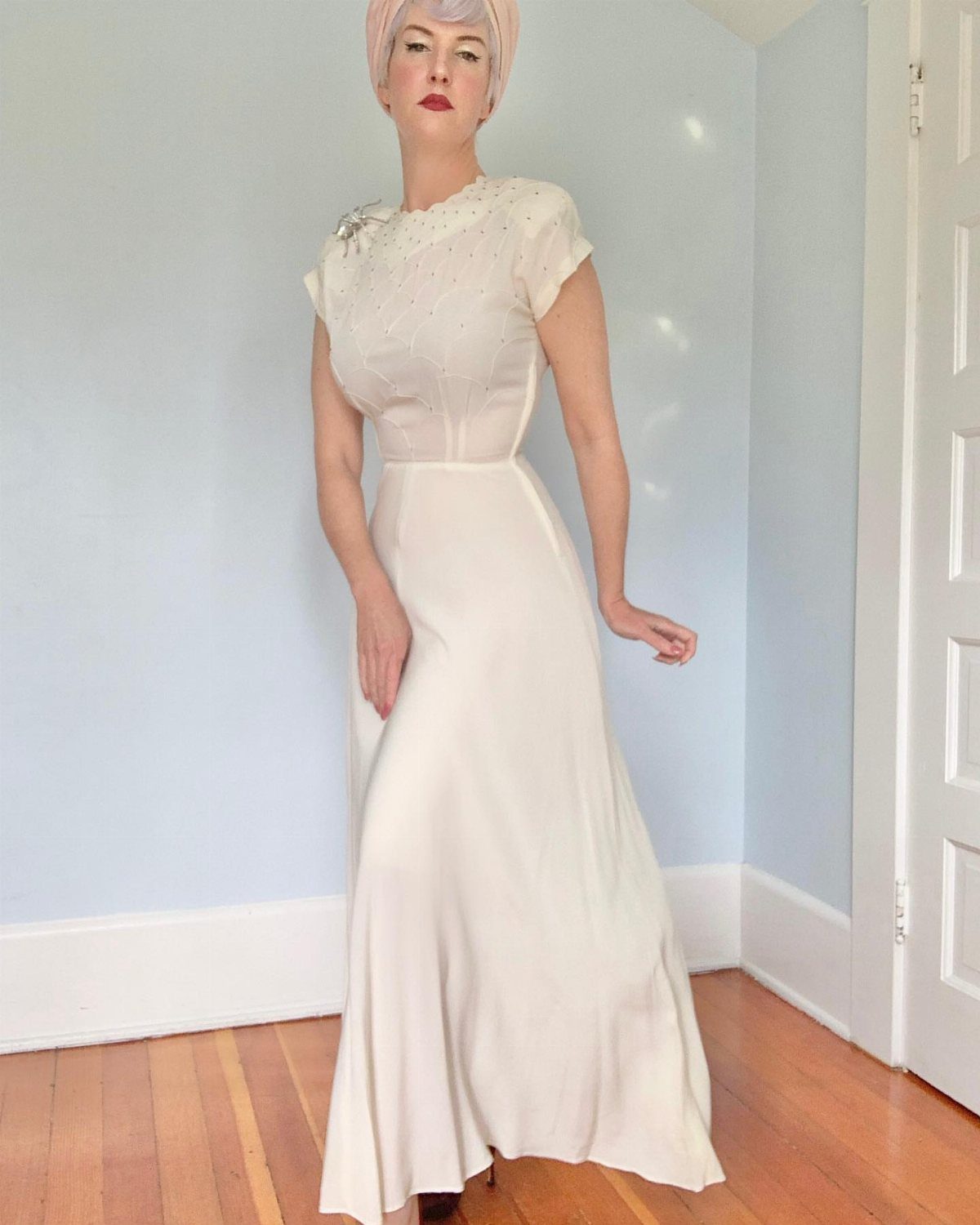 Woman in an off-white vintage bias cut gown with red lipstick and headwrap.