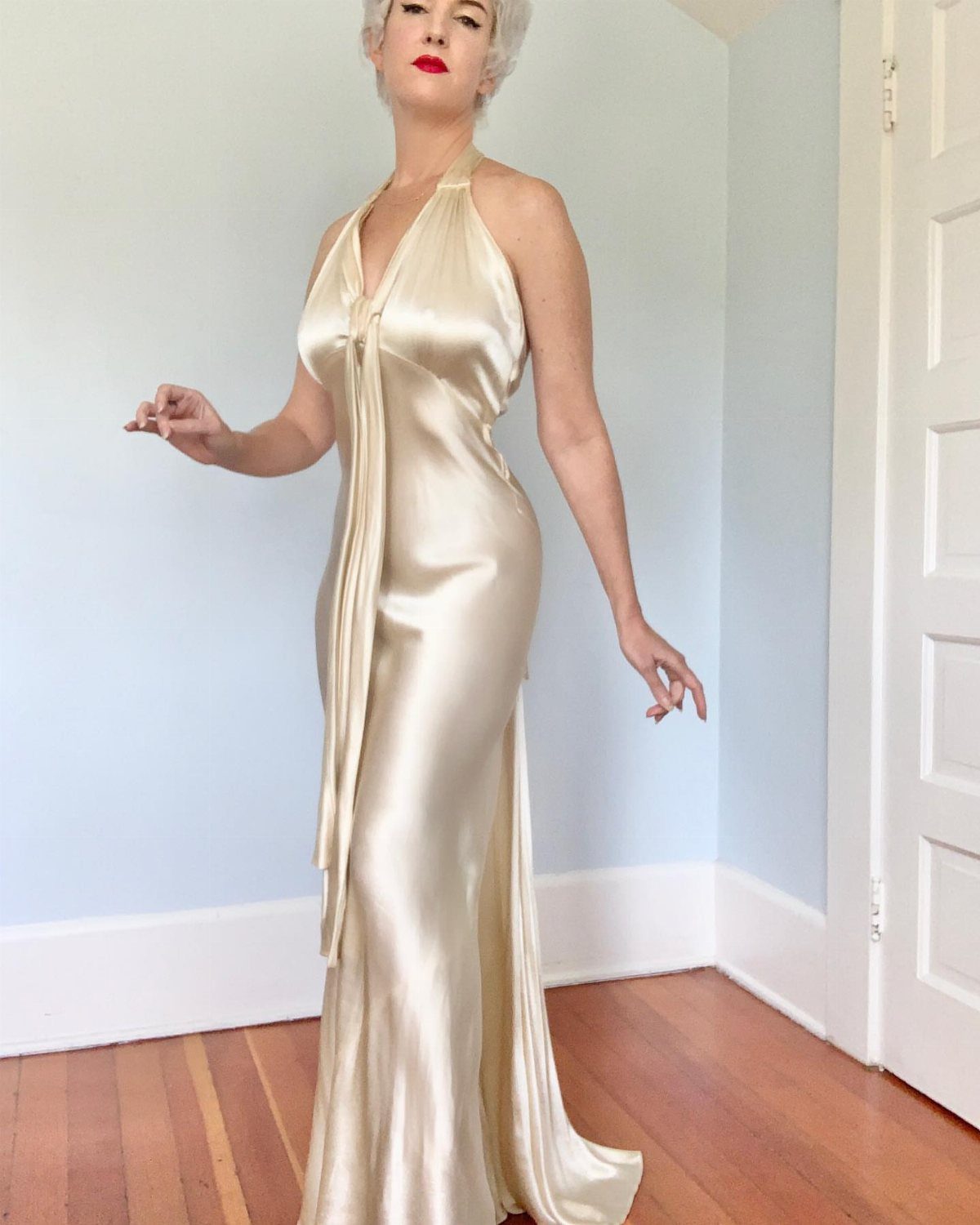 Woman in a champagne satin column dress with red lipstick and blonde hair.