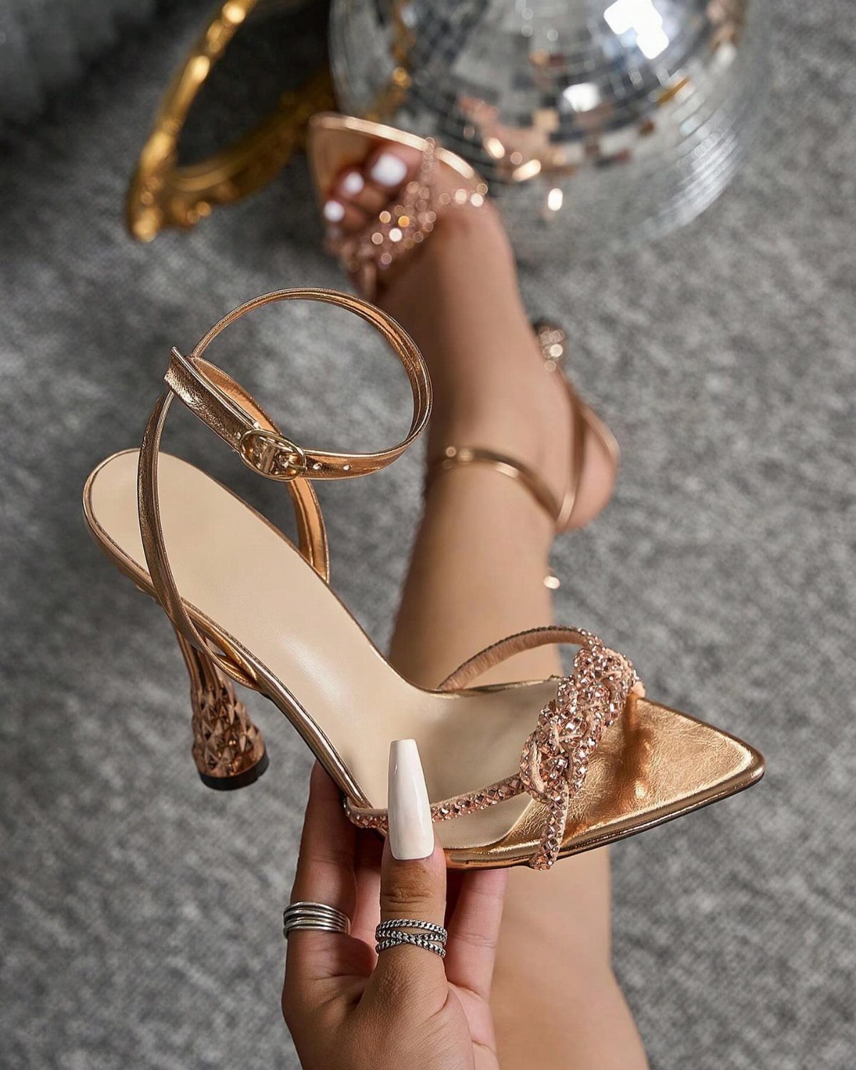 Rose gold metallic pointed-toe heels with rhinestone details and a slingback strap.