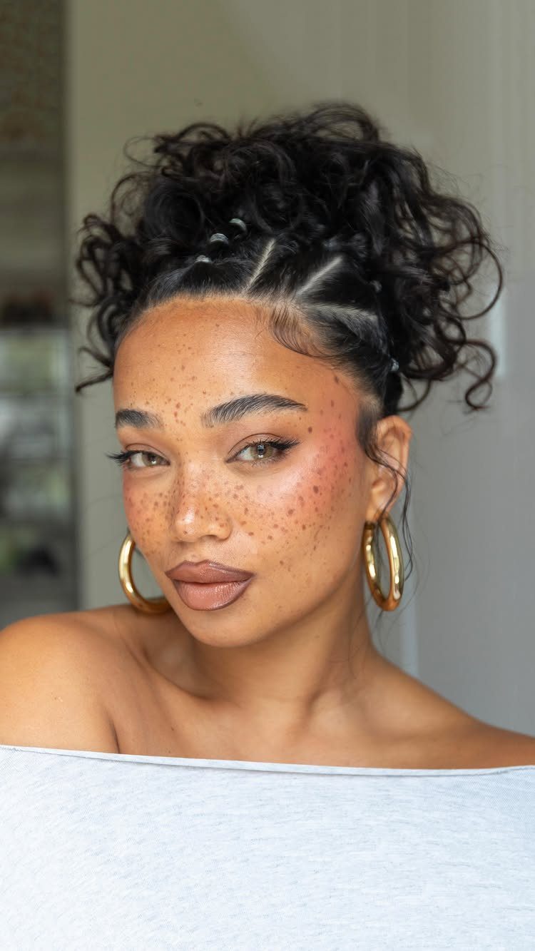 11 Peinado Pelo Rizado Ideas for Every Curl Type 10 Woman with freckles wearing a high curly bun with braided scalp details.