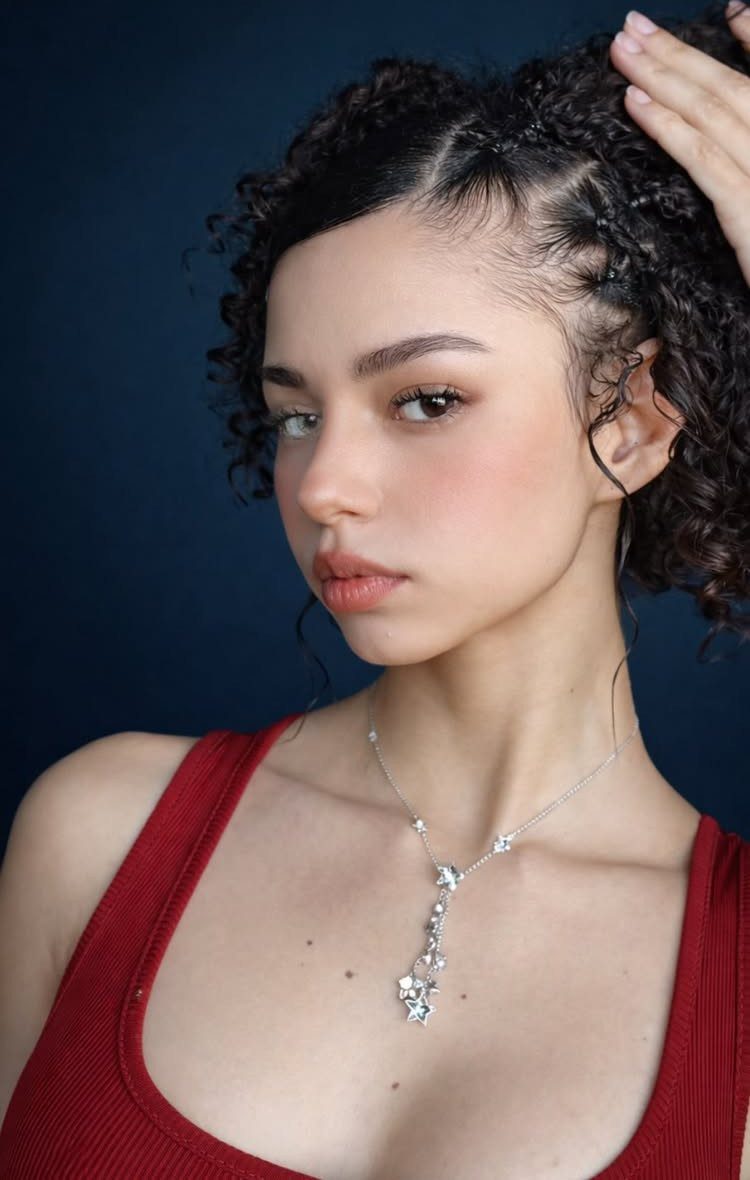 11 Peinado Pelo Rizado Ideas for Every Curl Type 8 Woman with dark curly hair in a braided half-updo wearing a red top.