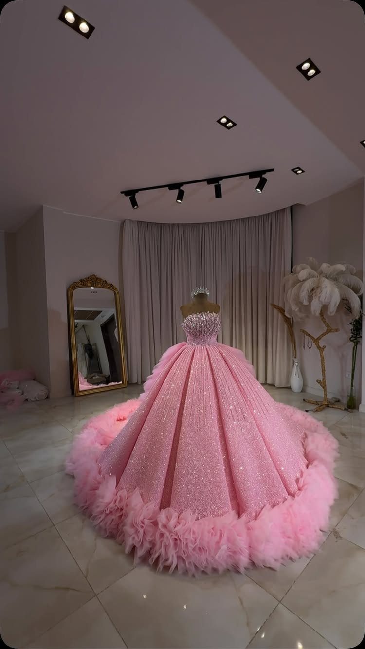 Pink Ballgown Wedding Dress: 8 Ideas with Bows and Feathers 8 Sparkling pink ballgown wedding dress with feathered hem on a mannequin in a studio.