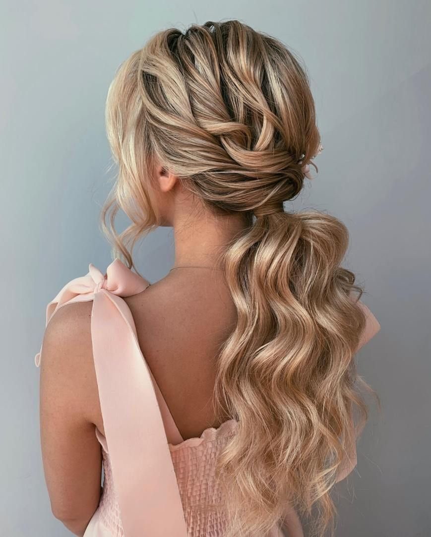 8 Prom Ponytail Hairstyles from Sleek to Curly 7 Blonde woman with a low ponytail featuring large curls and twisted crown details.