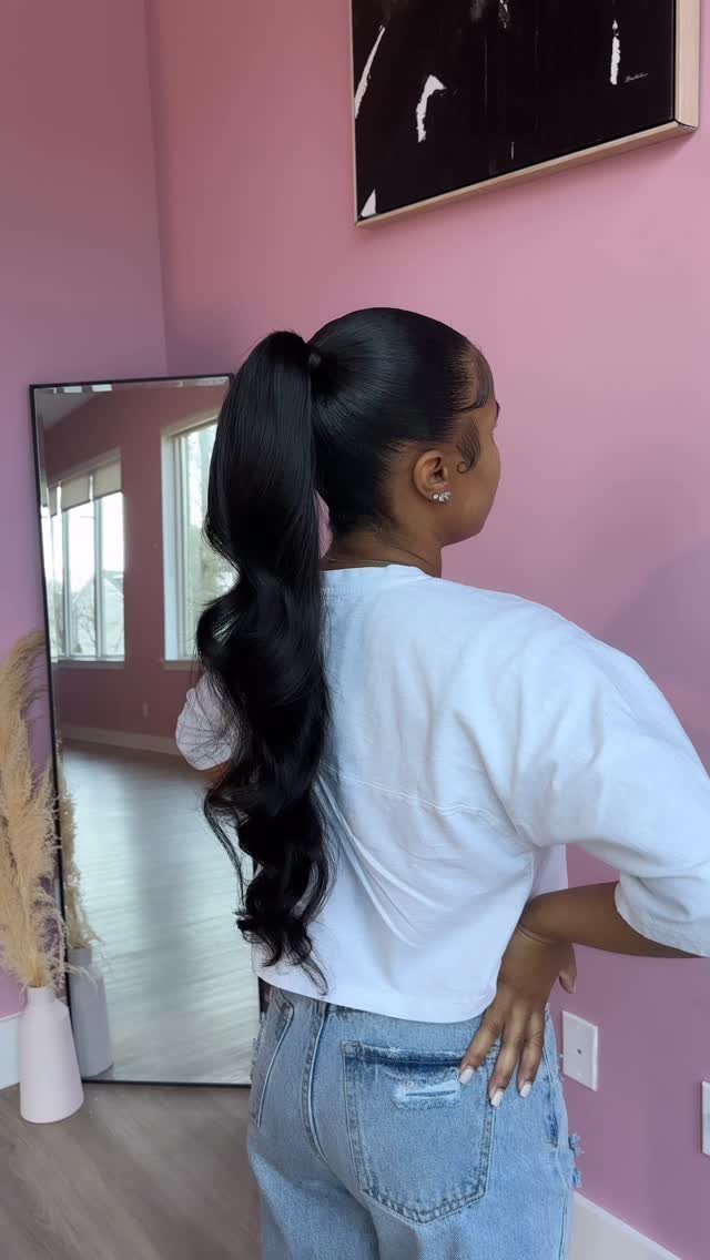 8 Prom Ponytail Hairstyles from Sleek to Curly 2 Woman with a sleek high ponytail and wavy ends wearing a white t-shirt.