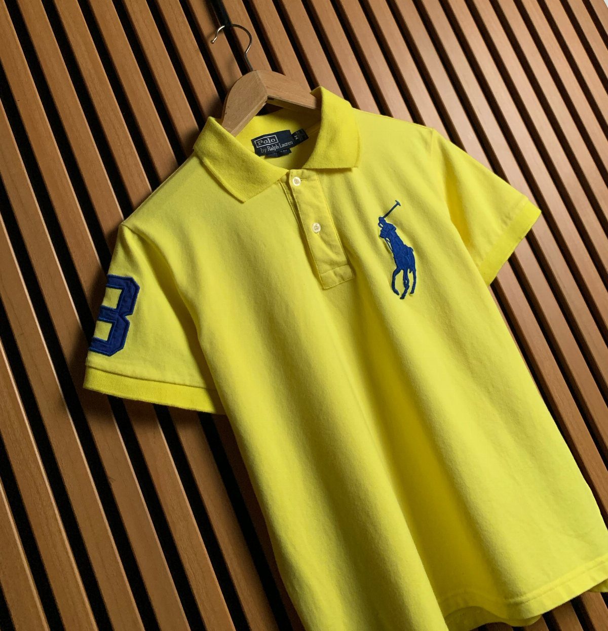 Ralph Lauren Yellow Polo Outfits: 6 Ways to Wear One 5 Yellow Ralph Lauren polo shirt with blue logo hanging on wooden wall