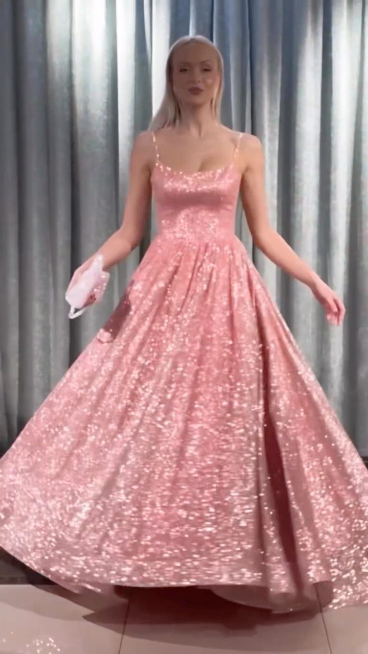Blonde woman in a sparkling pink sequined ball gown holding a white clutch.