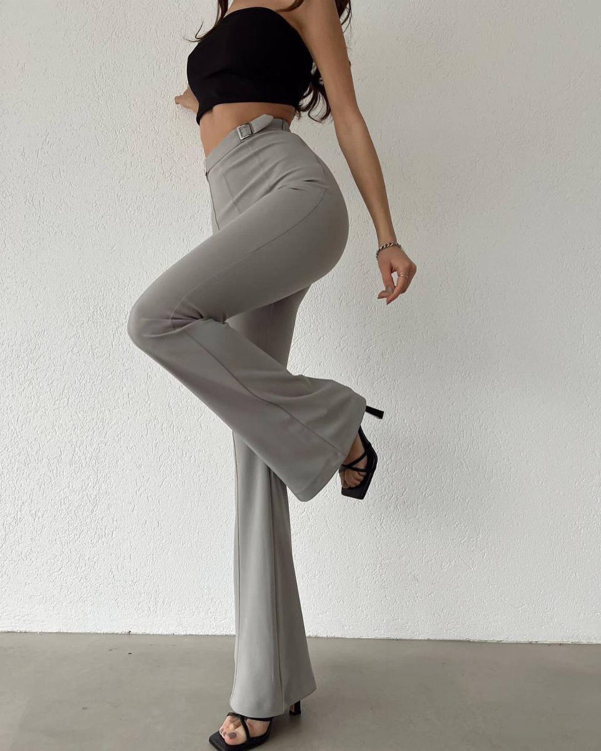 6 Retro Bell Bottoms Ideas for Every Closet and Mood 1 Person wearing high-waisted grey flared trousers and a black tube top posing.