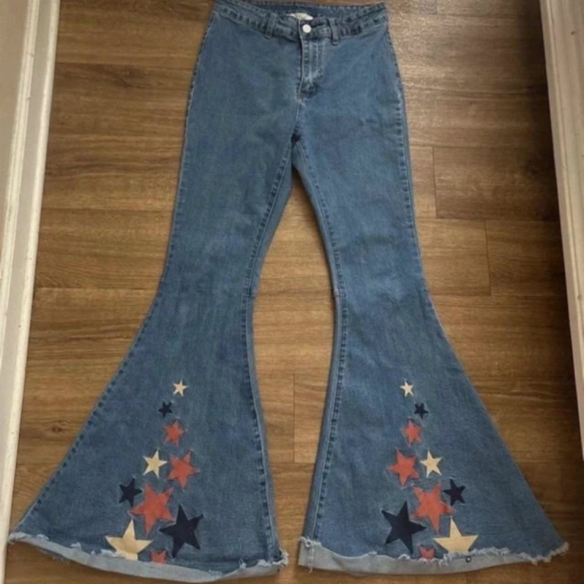 6 Retro Bell Bottoms Ideas for Every Closet and Mood 4 Blue denim bell-bottom jeans with colorful embroidered stars on the wide leg hems.