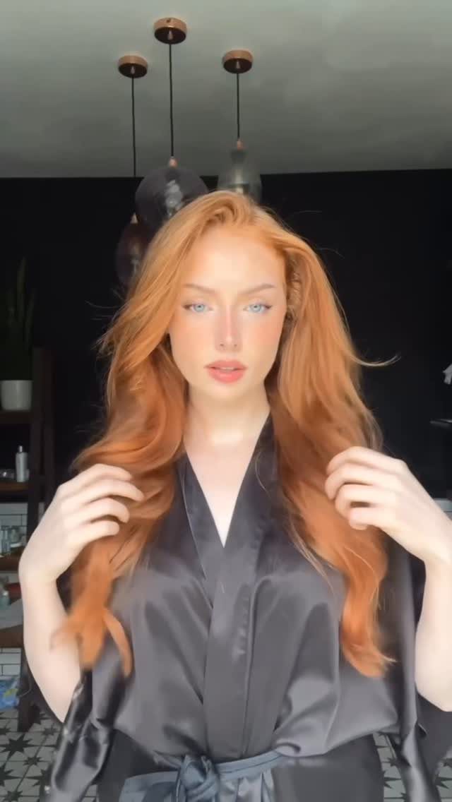 20 Summer Hair Dye Ideas, from Pastel Blue to Cool Raven 2 Woman with long wavy bright copper hair wearing a black satin robe.