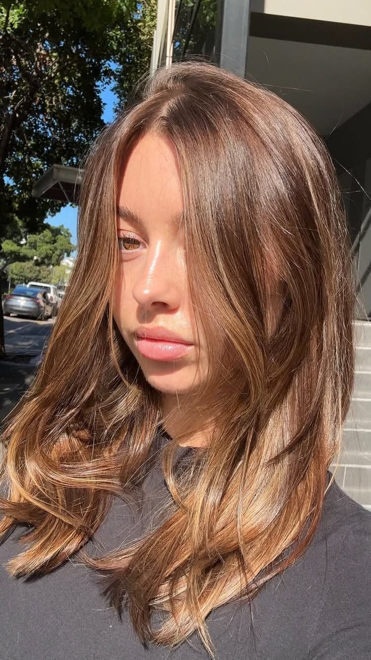 20 Summer Hair Dye Ideas, from Pastel Blue to Cool Raven 6 Woman with long wavy bronde hair blending brown and blonde tones in sunlight.