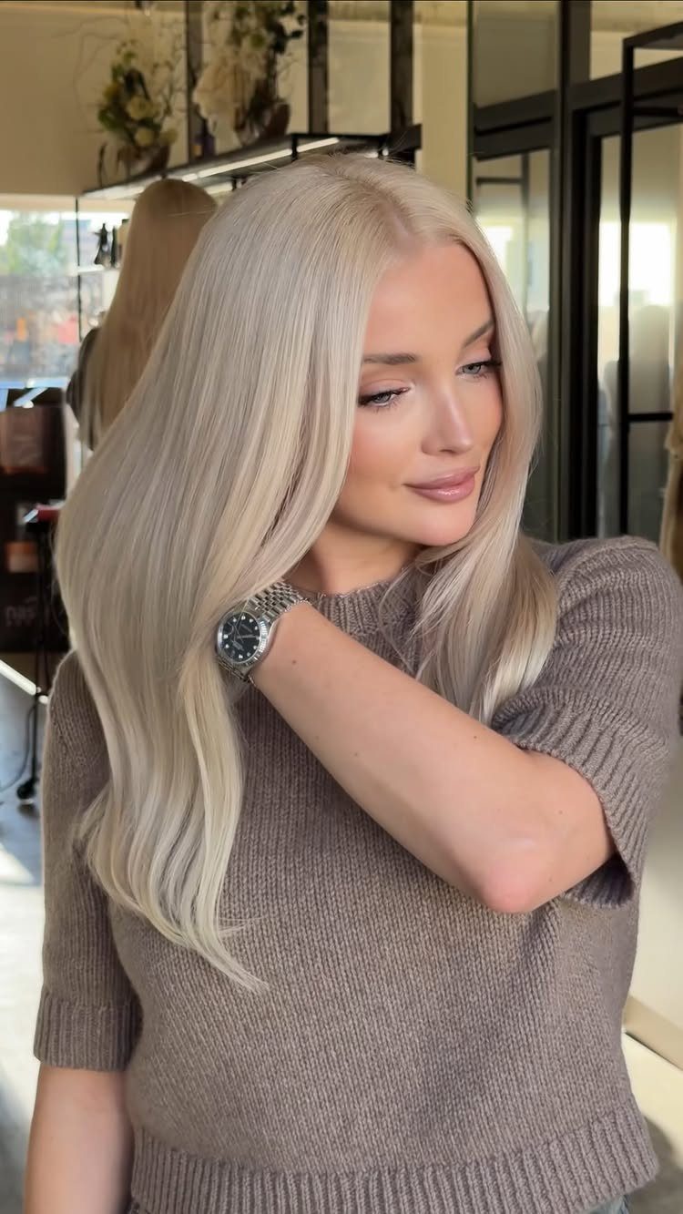 20 Summer Hair Dye Ideas, from Pastel Blue to Cool Raven 5 Woman with long icy blonde hair wearing a brown knit sweater and silver watch.