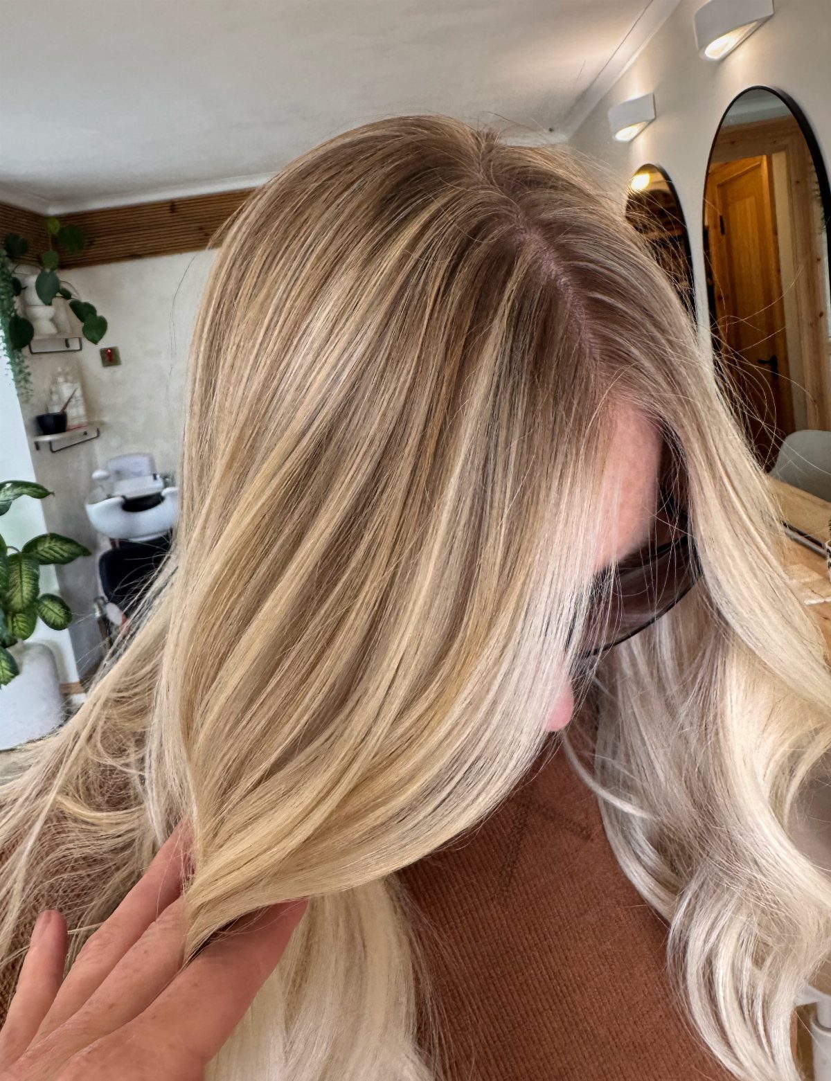 20 Summer Hair Dye Ideas, from Pastel Blue to Cool Raven 14 Sandy blonde wavy hair with darker roots on a person in a salon.
