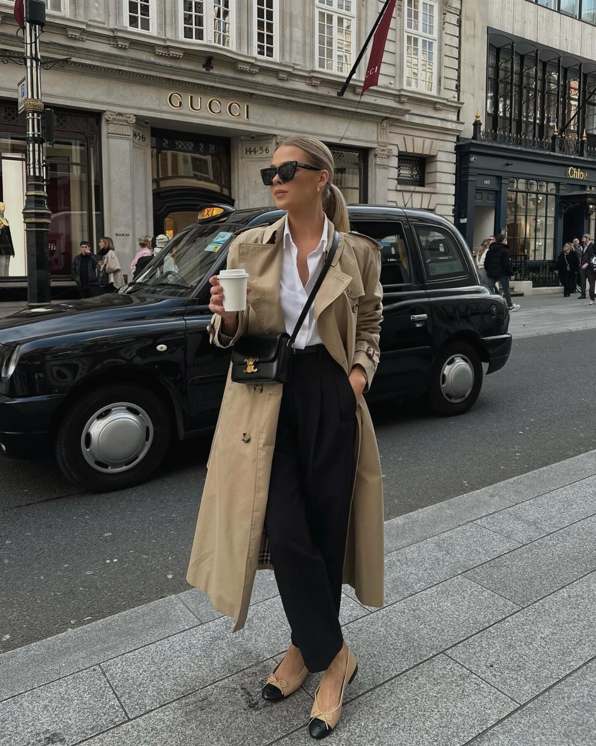 9 Trending Outfit Ideas for Women to Wear Right Now 4 Woman wearing a beige trench coat, white shirt, and black trousers on city street