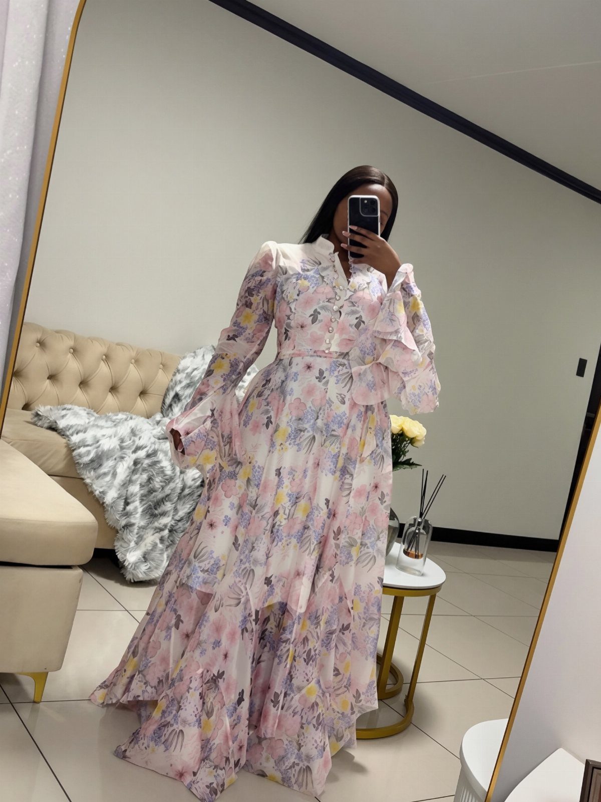 9 Trending Outfit Ideas for Women to Wear Right Now 8 Woman in a long-sleeved floral printed maxi dress taking a mirror selfie indoors.