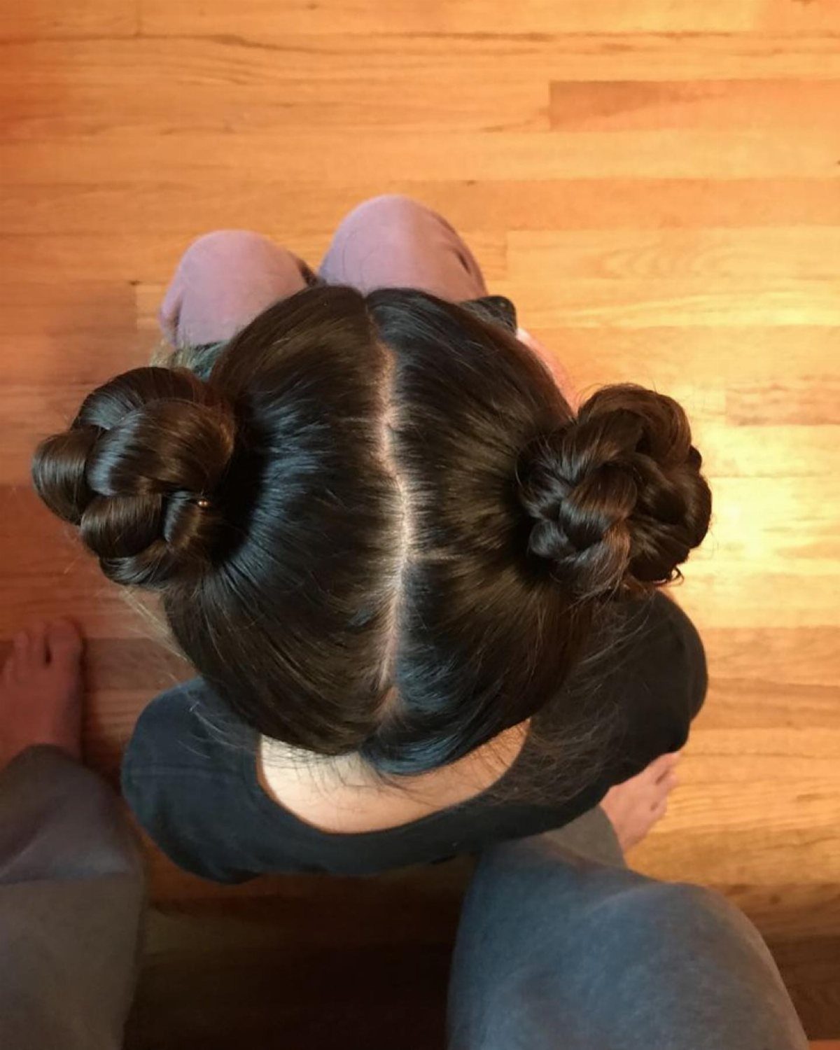 Two Braids with Bun Hairstyles: 4 Ideas to Try 1 Two braided buns on a person with dark brown hair, viewed from above.