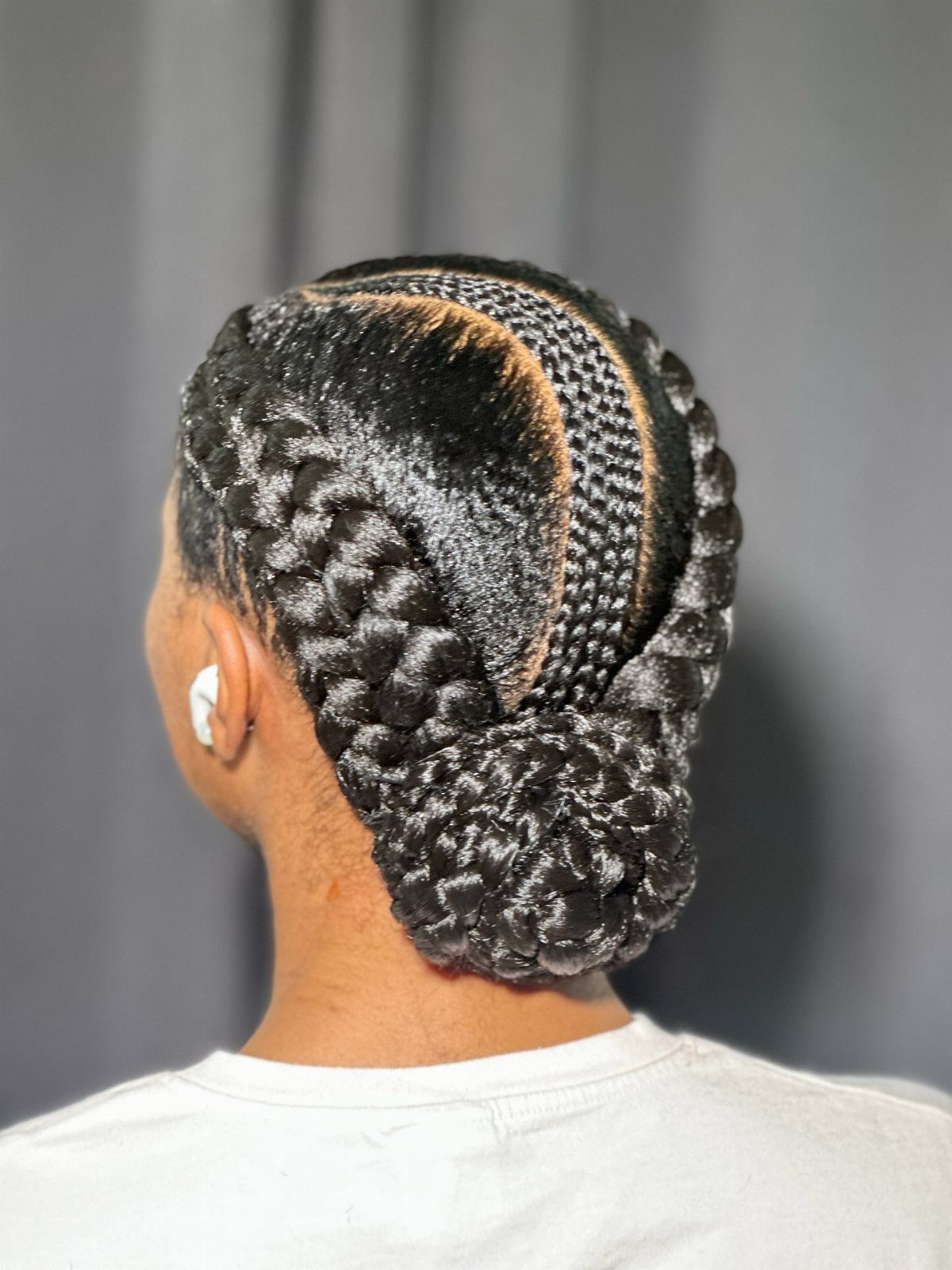 Two Braids with Bun Hairstyles: 4 Ideas to Try 3 Two thick Dutch braids coiled into a glossy bun on dark hair.
