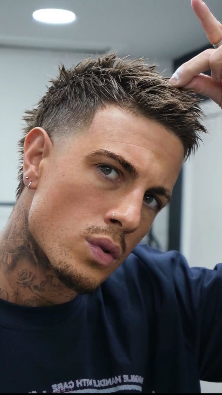Man with a spiky warrior cut hairstyle, faded sides, and neck tattoos.