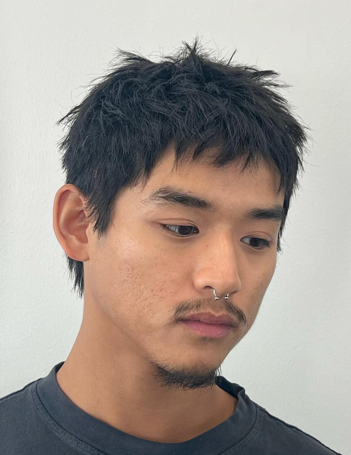 Man with a textured warrior fringe hairstyle, choppy black hair and facial hair.