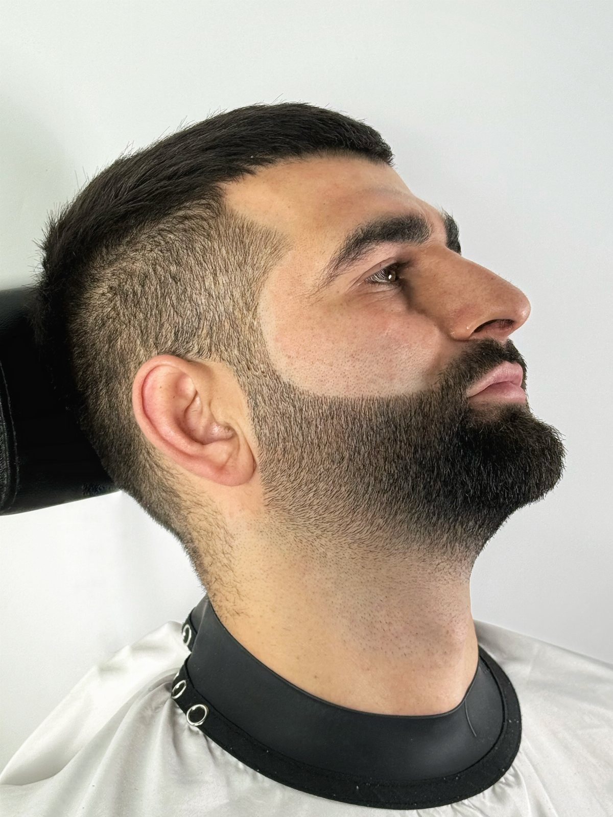 Man with a short warrior cut hairstyle and a well-groomed full dark beard.