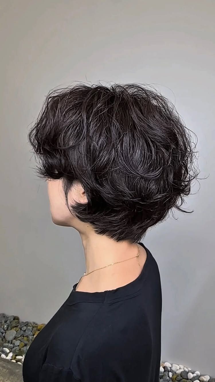 Wavy Hair Styles for Women: 12 Cuts and Looks to Try 2 Short dark wavy hair styled in a textured pixie cut on a woman.