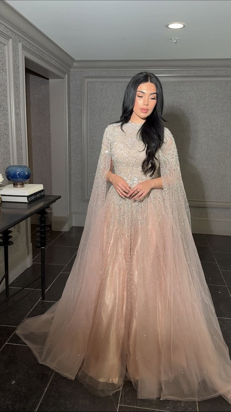 10 Wedding After Party Outfit Ideas for Guests 9 Woman wearing a shimmering champagne-colored beaded gown with a cape overlay.