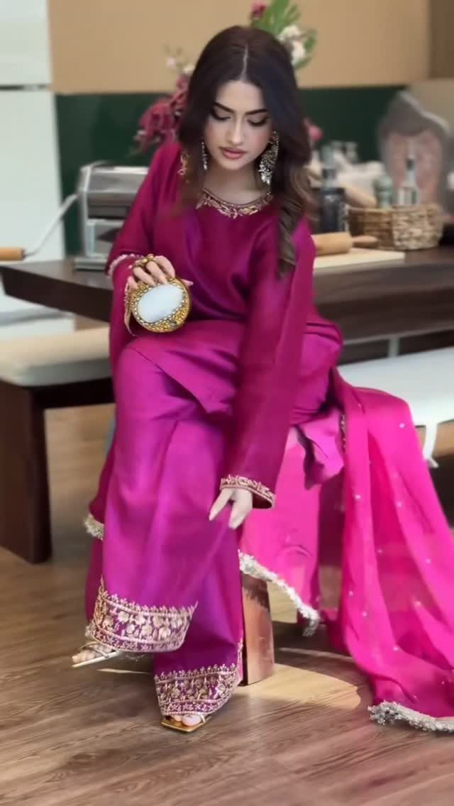 10 Wedding After Party Outfit Ideas for Guests 7 Woman in magenta silk salwar kameez with gold embroidery holding a gold clutch.