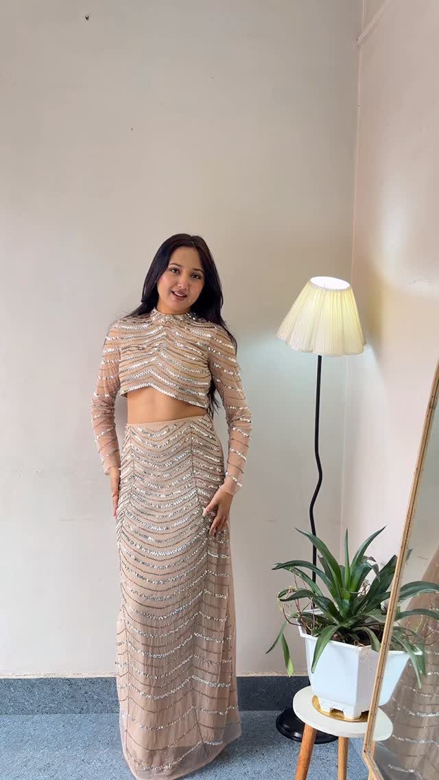 10 Wedding After Party Outfit Ideas for Guests 5 Woman in a champagne sequined two-piece set with a cropped top and long skirt.