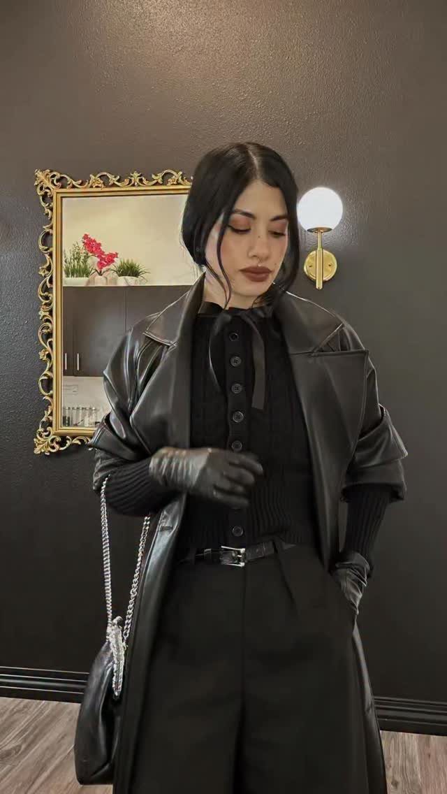 Woman in all-black winter goth attire including a leather coat and gloves.