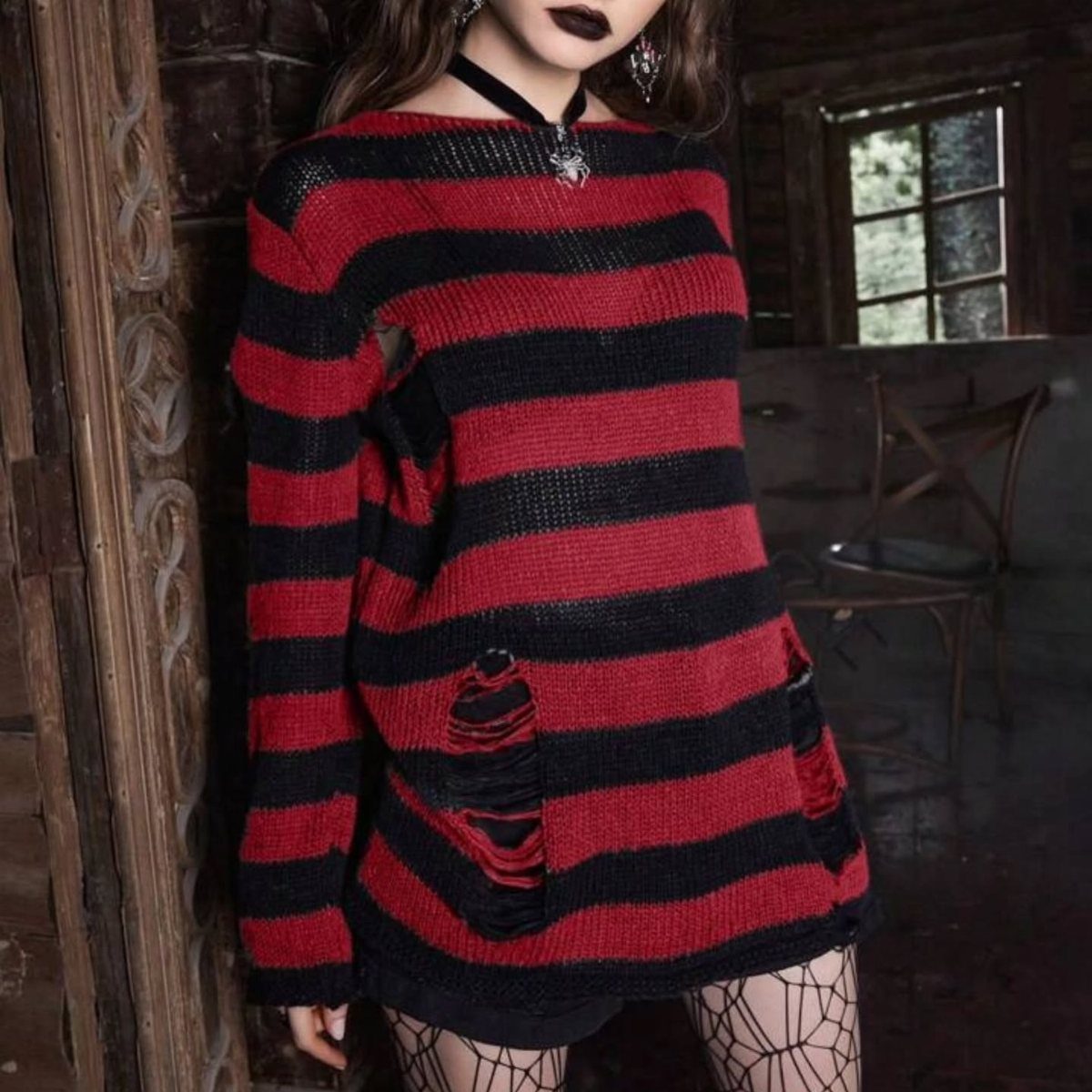 Person in red and black striped sweater with spiderweb tights in rustic room